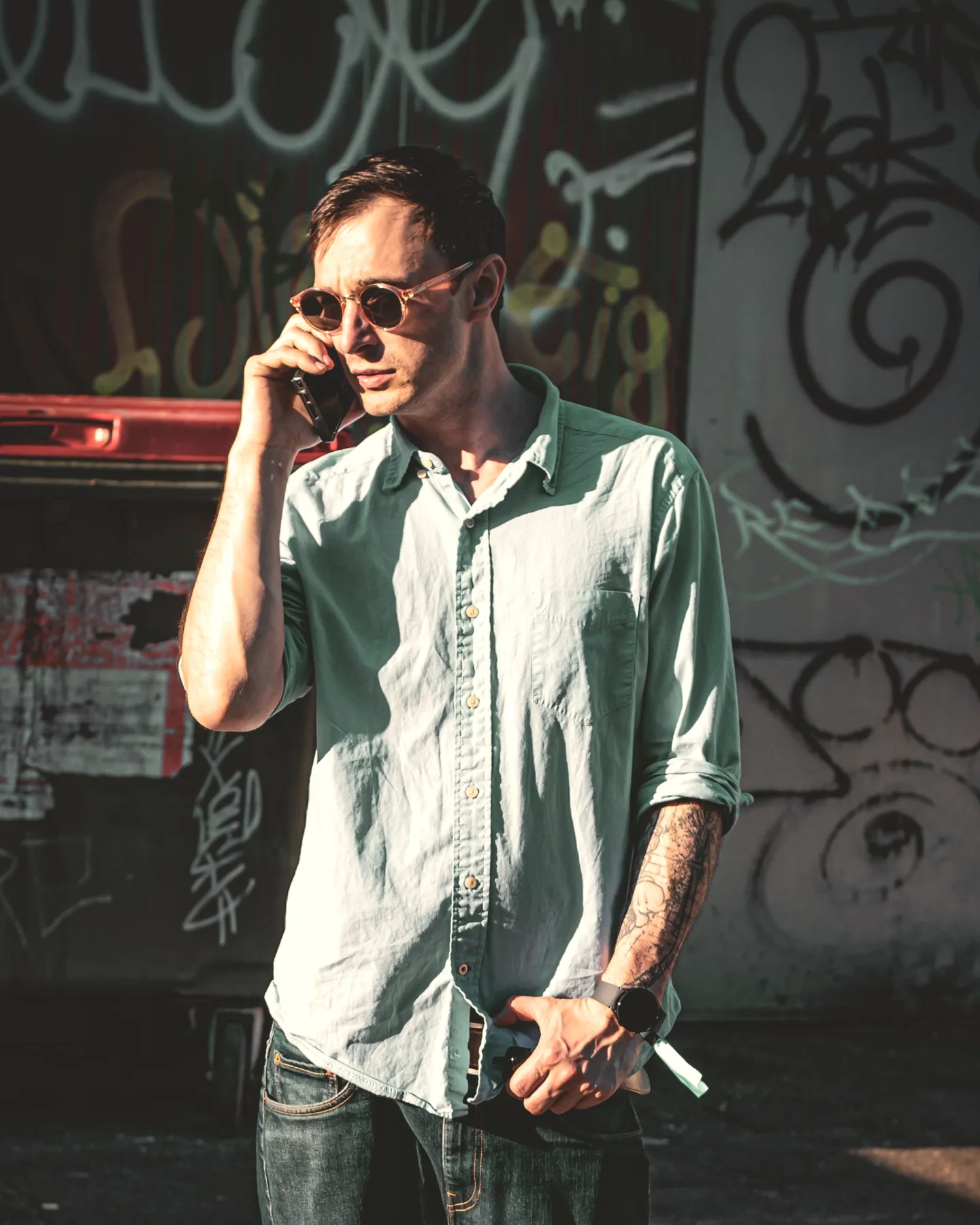 Jack Alexander on the phone outside, in front of a painted wall